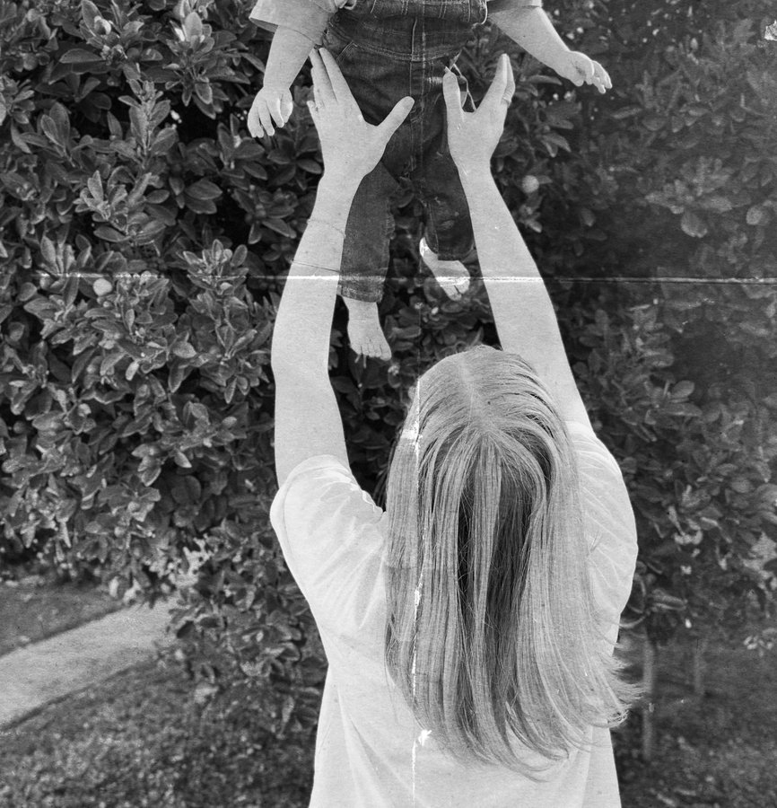 em throwing her child up in the air, laughing